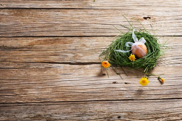 Egg with ribbon in a nest with flowers — Stock Photo, Image